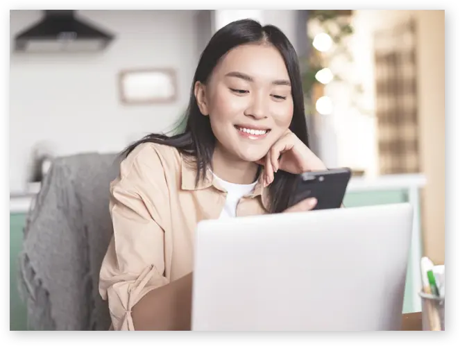 パソコンの前でスマホを触る女性